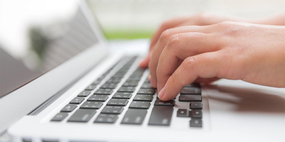 Fingers typing on laptop keyboard.